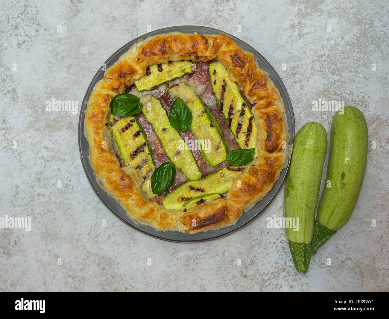 torta salata con zucchine e basilico su un piatto rotondo Foto Stock