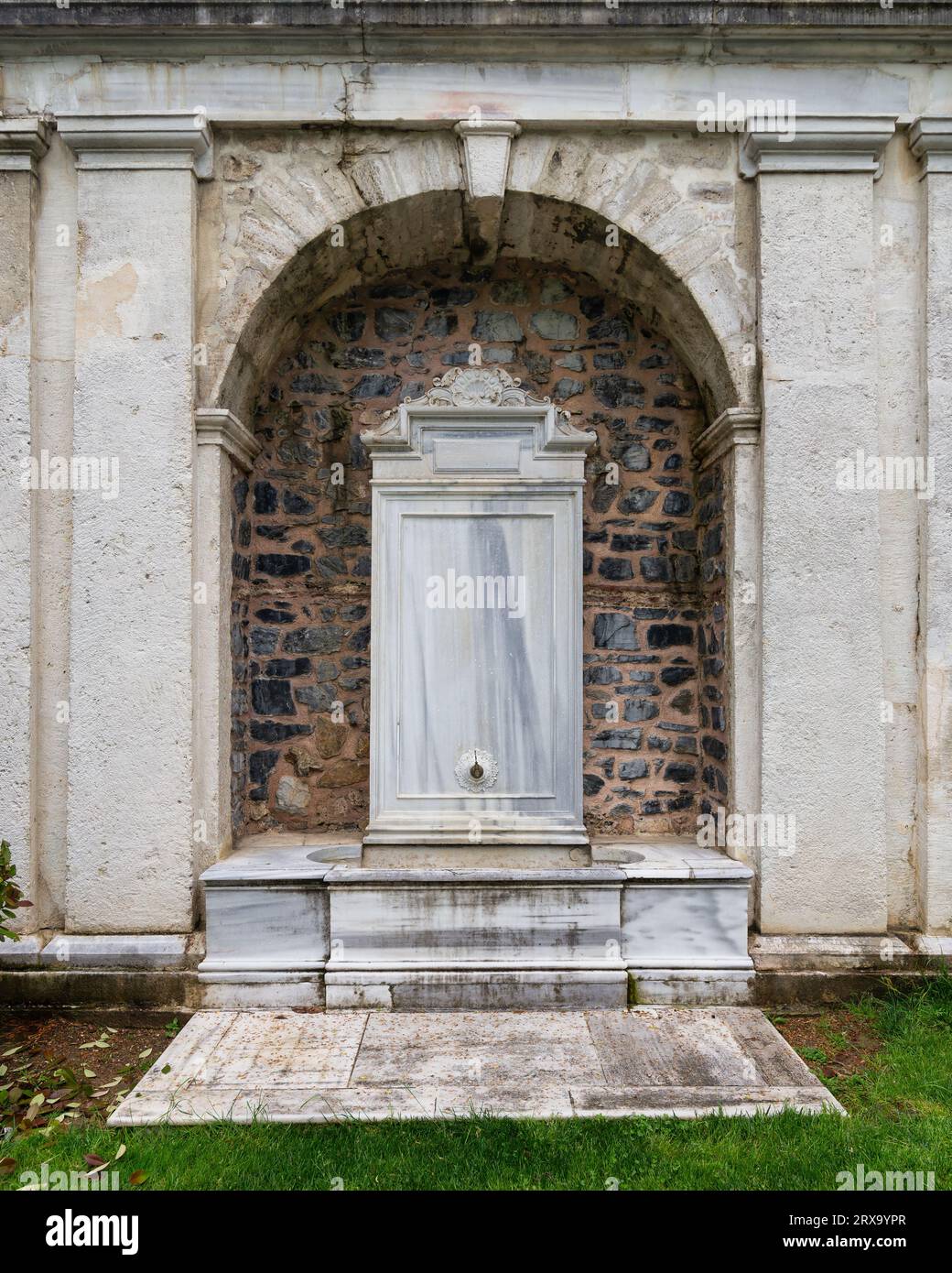 Una splendida fontana in marmo bianco situata nel giardino del Padiglione Mecidiye, Istanbul, Turchia. La fontana è circondata da un muro di pietra e presenta intricati intagli e disegni Foto Stock