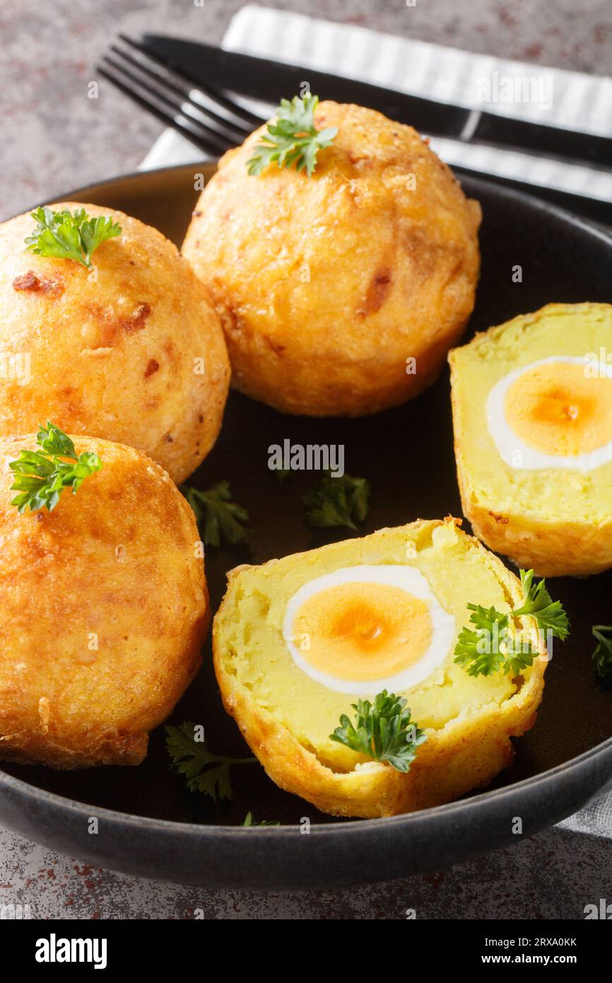 Purea di cassava ripiena di uovo e fritta in profondità in un piatto sul tavolo. Verticale Foto Stock