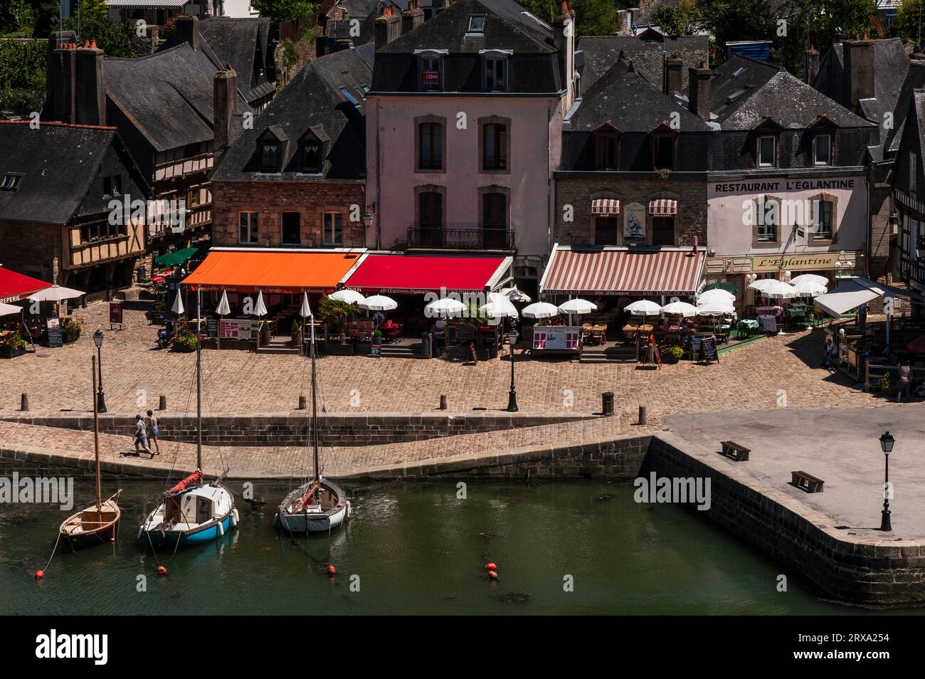 Tende da sole rosse e arancioni, tavoli e ombrelloni per mangiare all'aperto sulla banchina di Place Saint-Sauveur nel quartiere Saint-Goustan di Auray, una città sul lago del fiume nella Bretagna meridionale, in Francia. Foto Stock