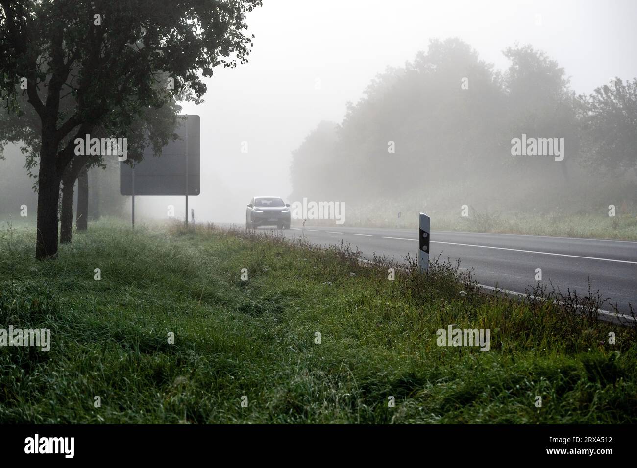 Pfarrweisach, Germania. 24 settembre 2023. Un'auto sta guidando con le luci accese su una strada nebbiosa vicino a Ebern (distretto di Haßberge, bassa Franconia). Oggigiorno, vi è ancora un aumento del rischio di incidenti a causa della scarsa visibilità. Crediti: Pia Bayer/dpa/Alamy Live News Foto Stock