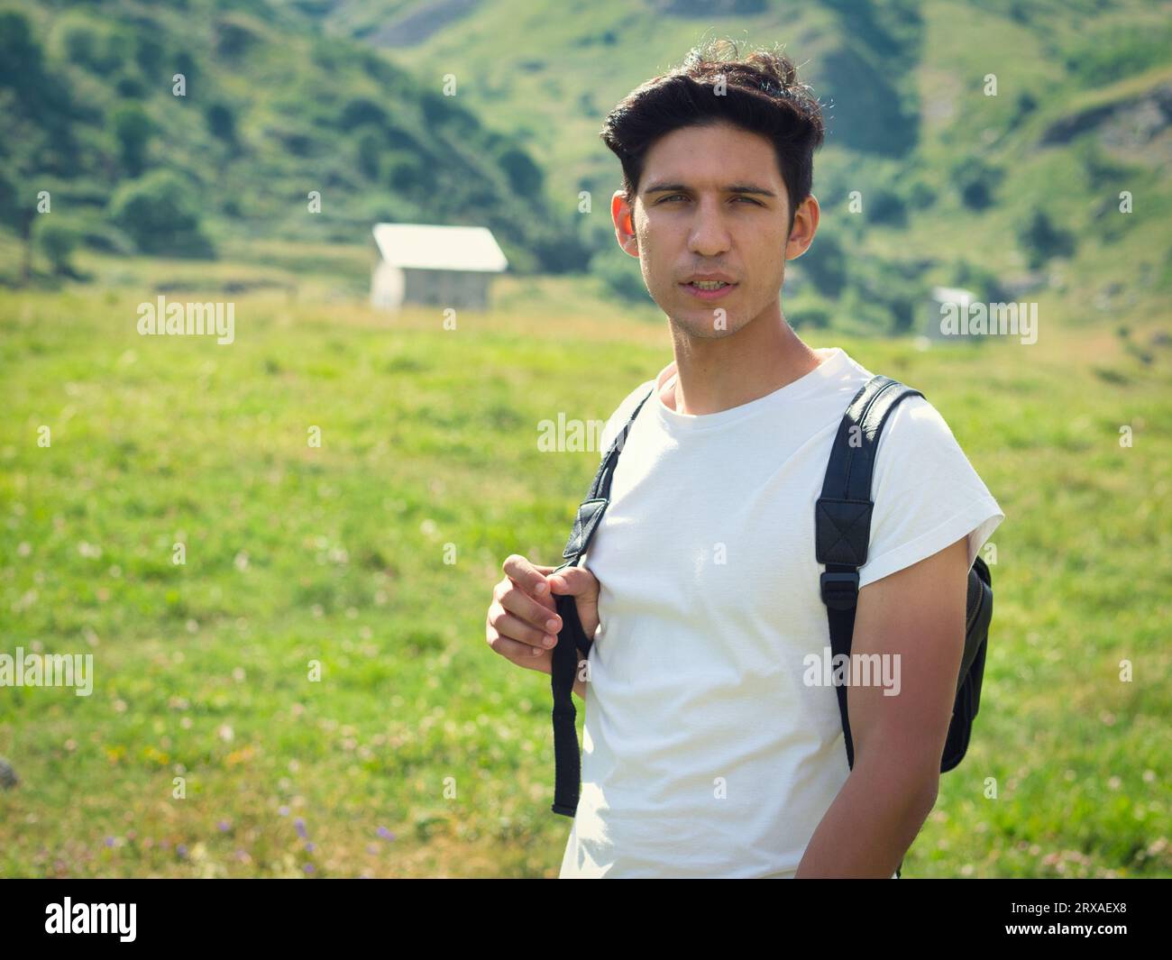 Un uomo con uno zaino in piedi in un campo. Foto di un giovane uomo attraente in piedi in un campo con uno zaino durante un'avventura escursionistica Foto Stock