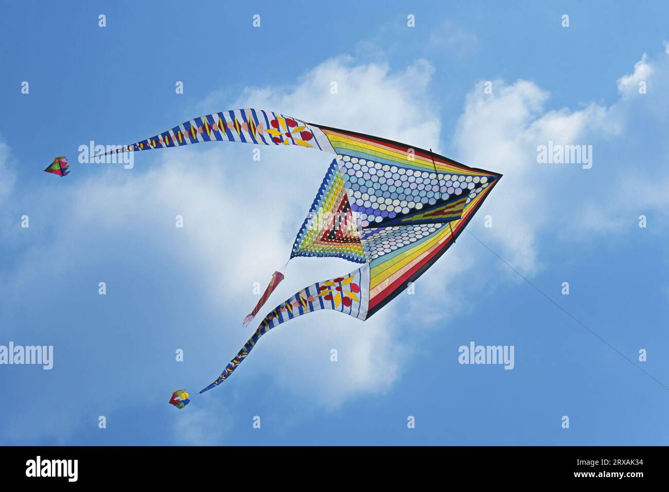 Aquilone a forma di romboide con disegni geometrici multicolori in volo Foto Stock