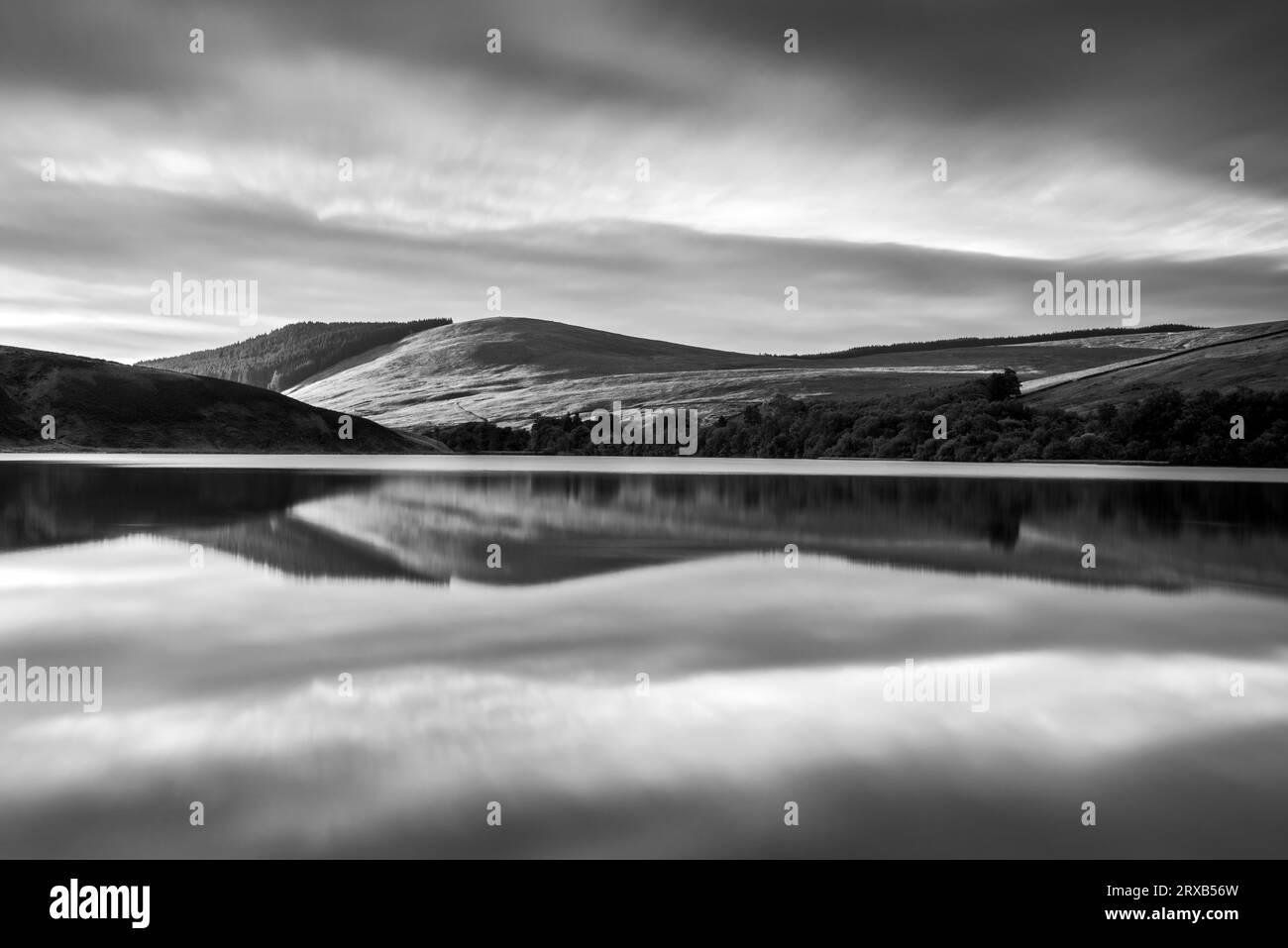 Un'immagine in bianco e nero di un'alba riflessa nelle acque di Glenbuck Loch vicino a Muirkirk nell'East Ayrshire, in Scozia. Foto Stock