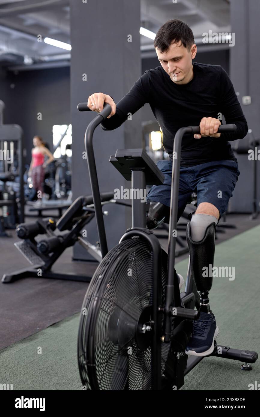 ragazzo slim-fit che utilizza la cyclette al centro sportivo, foto a tutta lunghezza Foto Stock