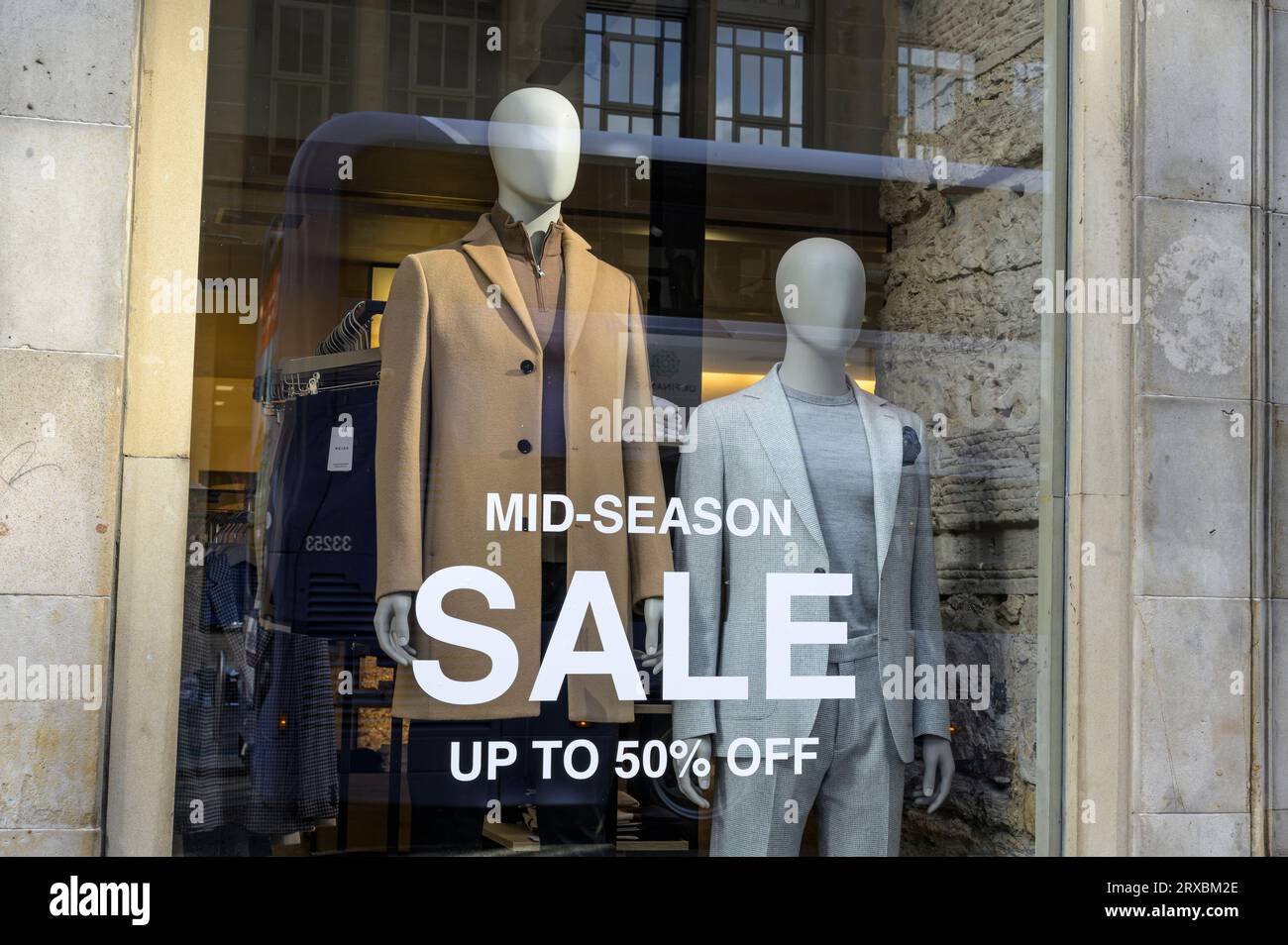 Saldi di mezza stagione fino al 50% di sconto su un cartello in una vetrina che mostra abbigliamento da uomo, Glasgow, Scozia, Regno Unito, Europa Foto Stock