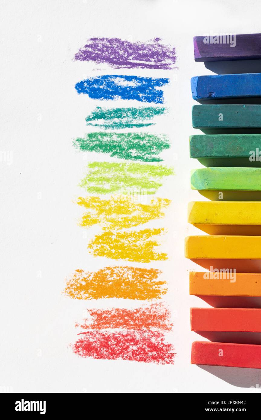 Chalk pastello asciutto nei colori dell'arcobaleno su sfondo bianco con spazio di testo a sinistra Foto Stock