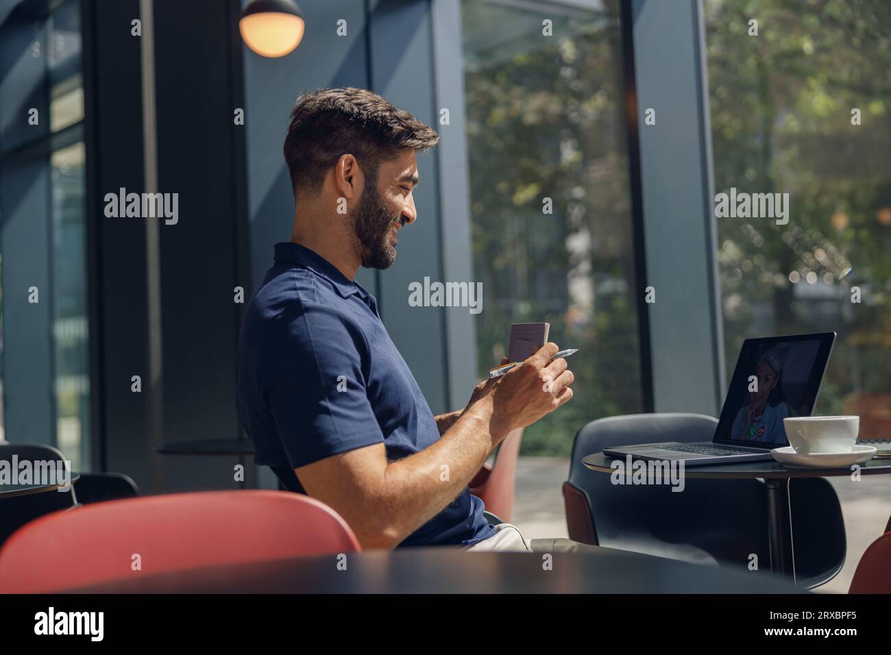 Bel freelance maschio che prende ordine dal cliente tramite webcam seduto in coworking Foto Stock