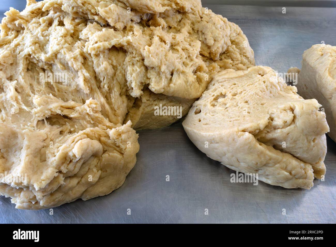 L'impasto per la pasta con crosta d'acqua fredda viene preparato su un tavolo di metallo. Vista laterale pronta per porzioni. Foto Stock