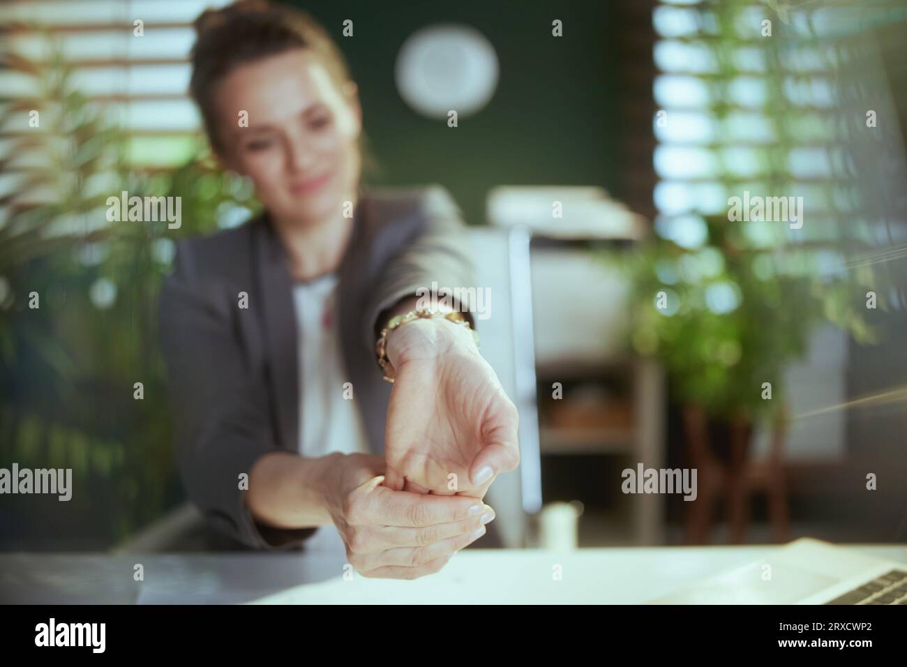 Ambiente di lavoro sostenibile. donna d'affari moderna sorridente al lavoro che si allunga le mani. Foto Stock