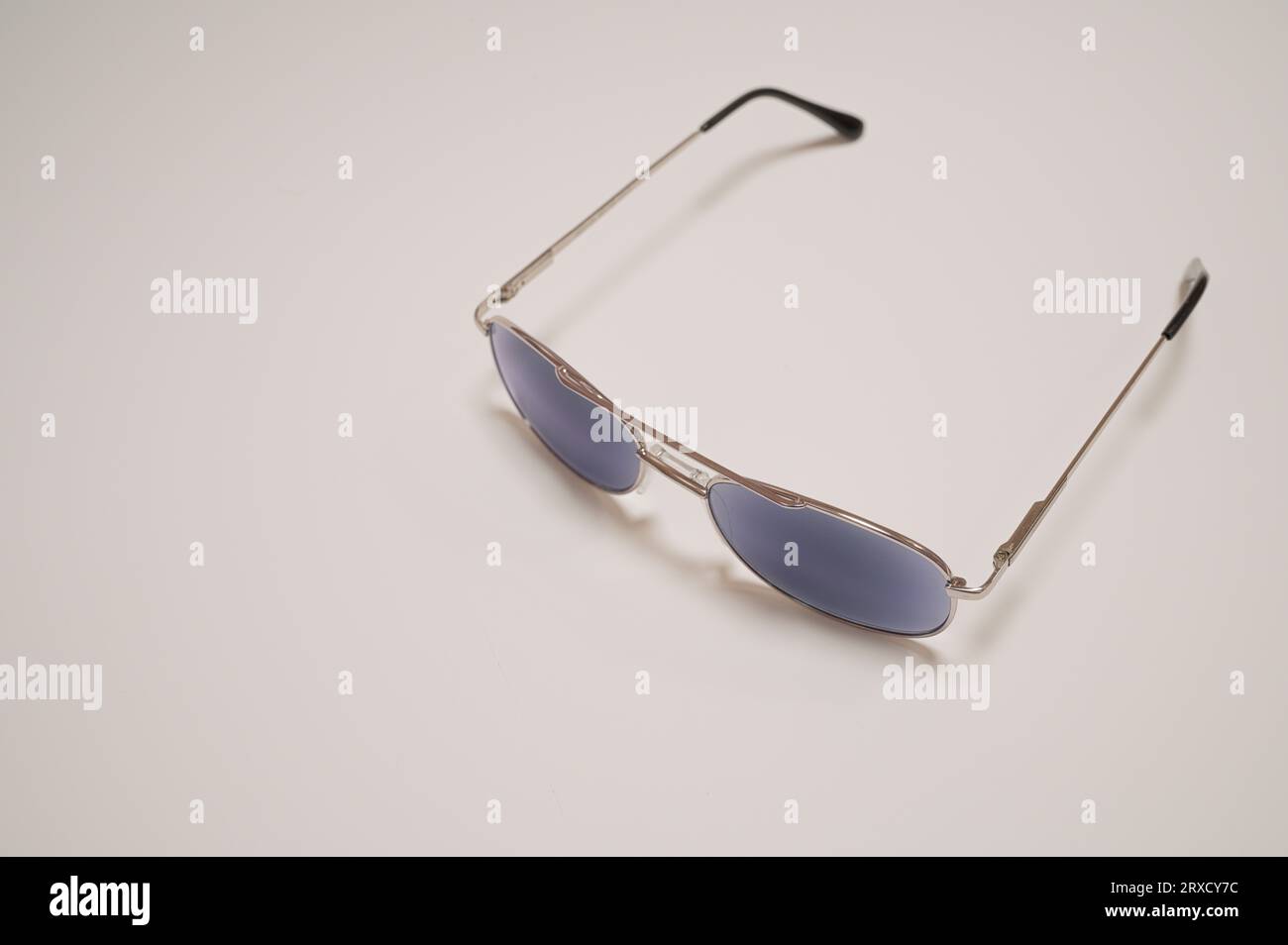 occhiali da sole con montature in acciaio e vetro blu su sfondo bianco Foto Stock