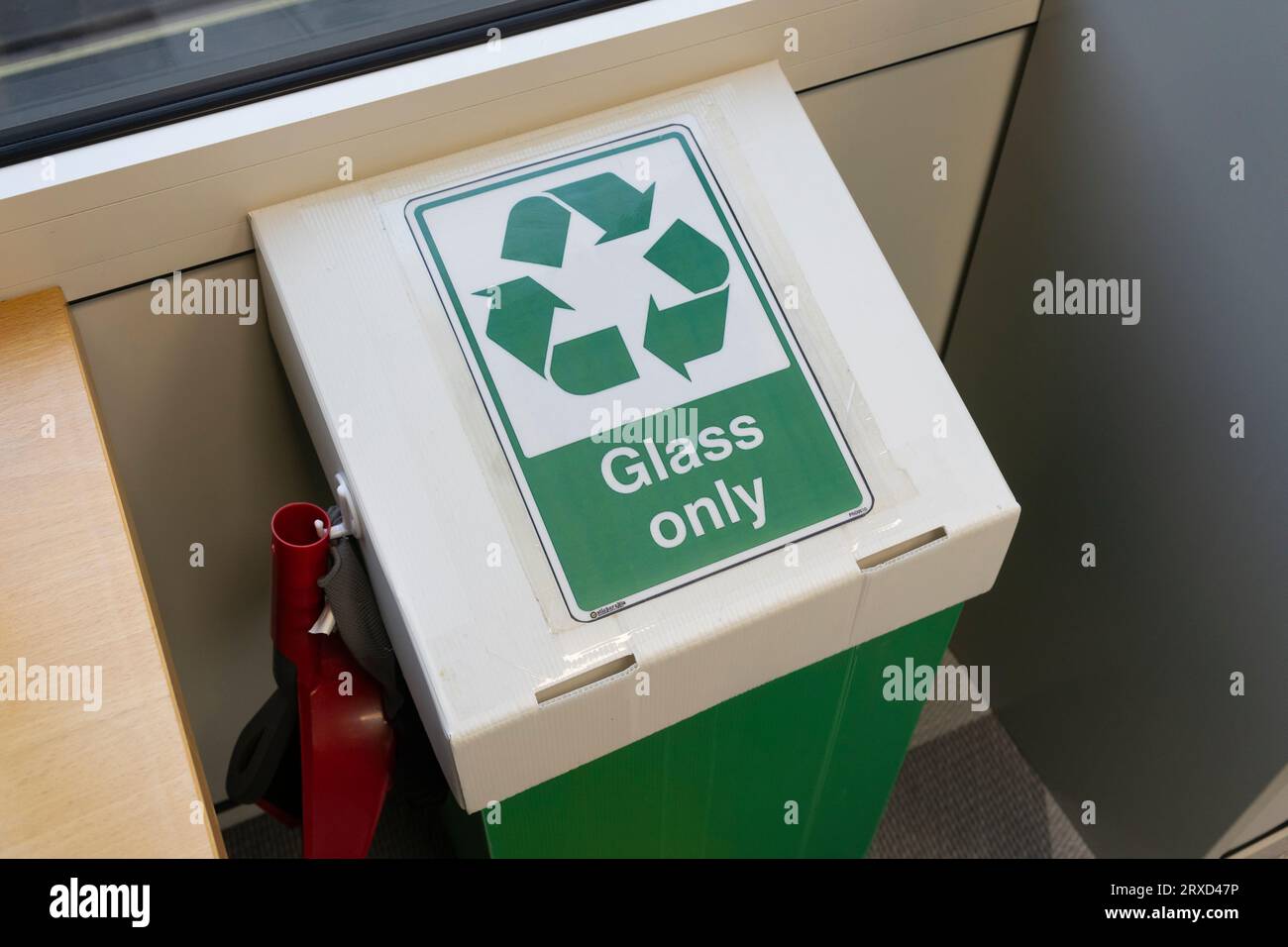 Una scatola di riciclaggio in vetro in un ufficio del Regno Unito con un simbolo di riciclaggio. Concetto: Riciclaggio aziendale, credenziali ecologiche, riciclaggio per ufficio, smaltimento dei vetri Foto Stock