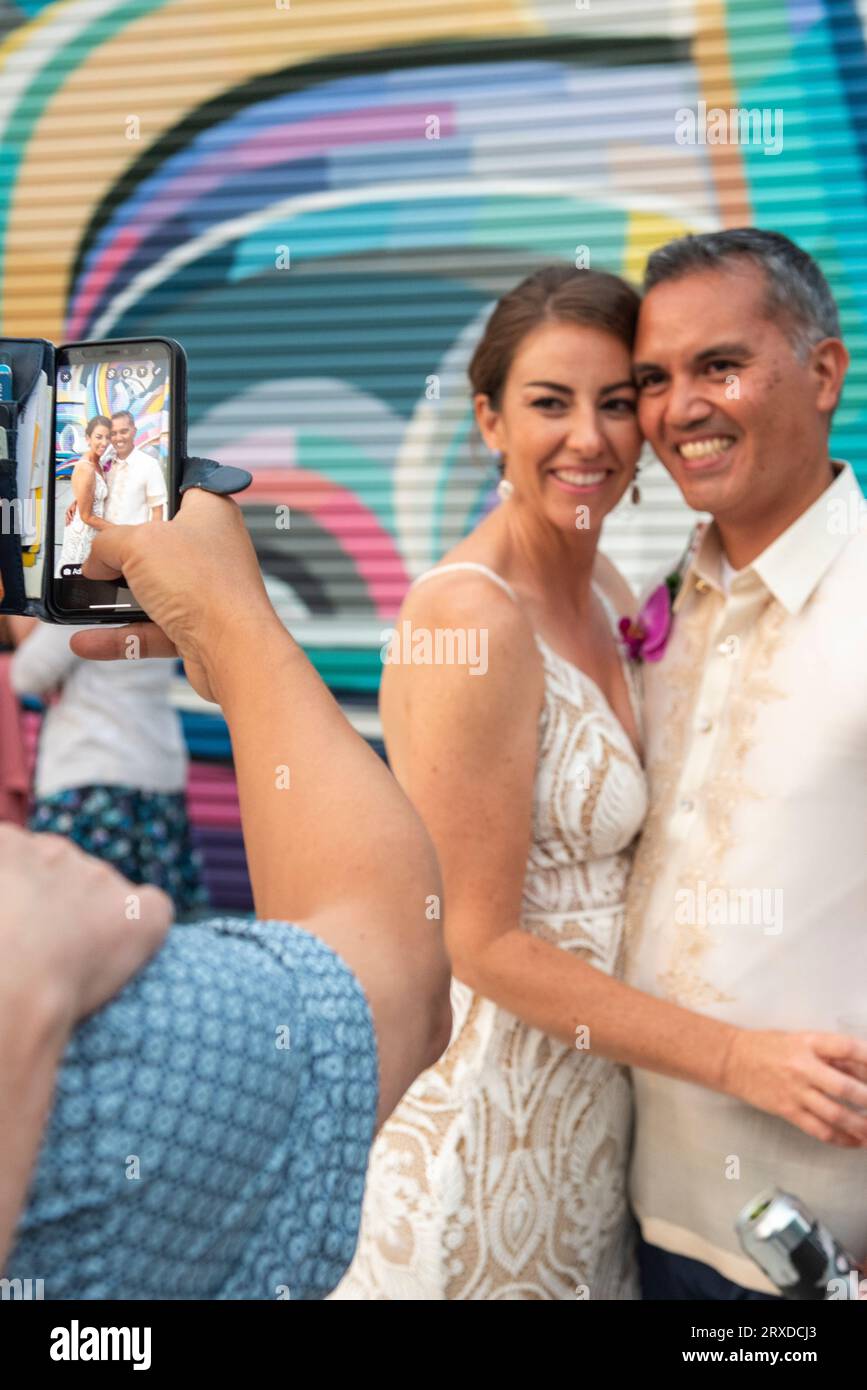 Un ospite di matrimonio scatta una foto di una sposa e di uno sposo al ricevimento di nozze. Foto Stock