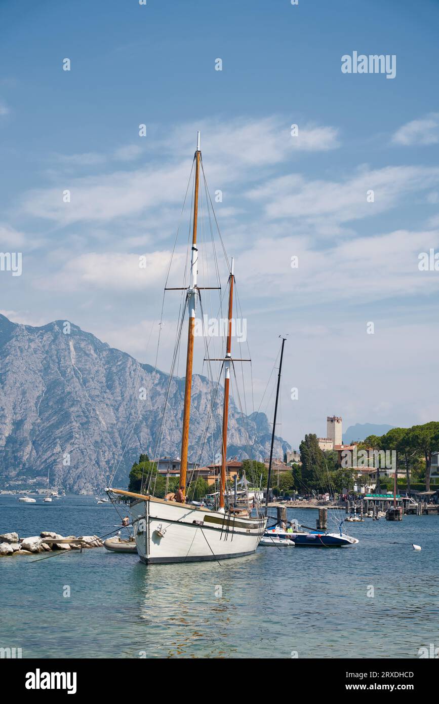 Yacht a vela per escursioni con turisti sul Lago di Garda vicino Malcesine in Italia. Sullo sfondo la città vecchia con il Castello Scaligero Foto Stock