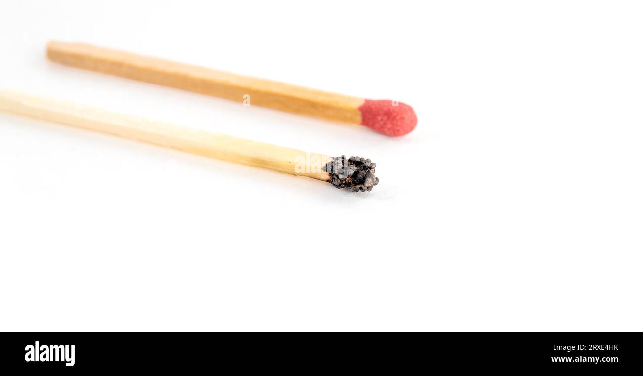 Primo piano di una partita bruciata e di una nuovissima partita isolata su sfondo bianco. Individualità e leadership, esaurimento del lavoro e dell'energia. Foto Stock