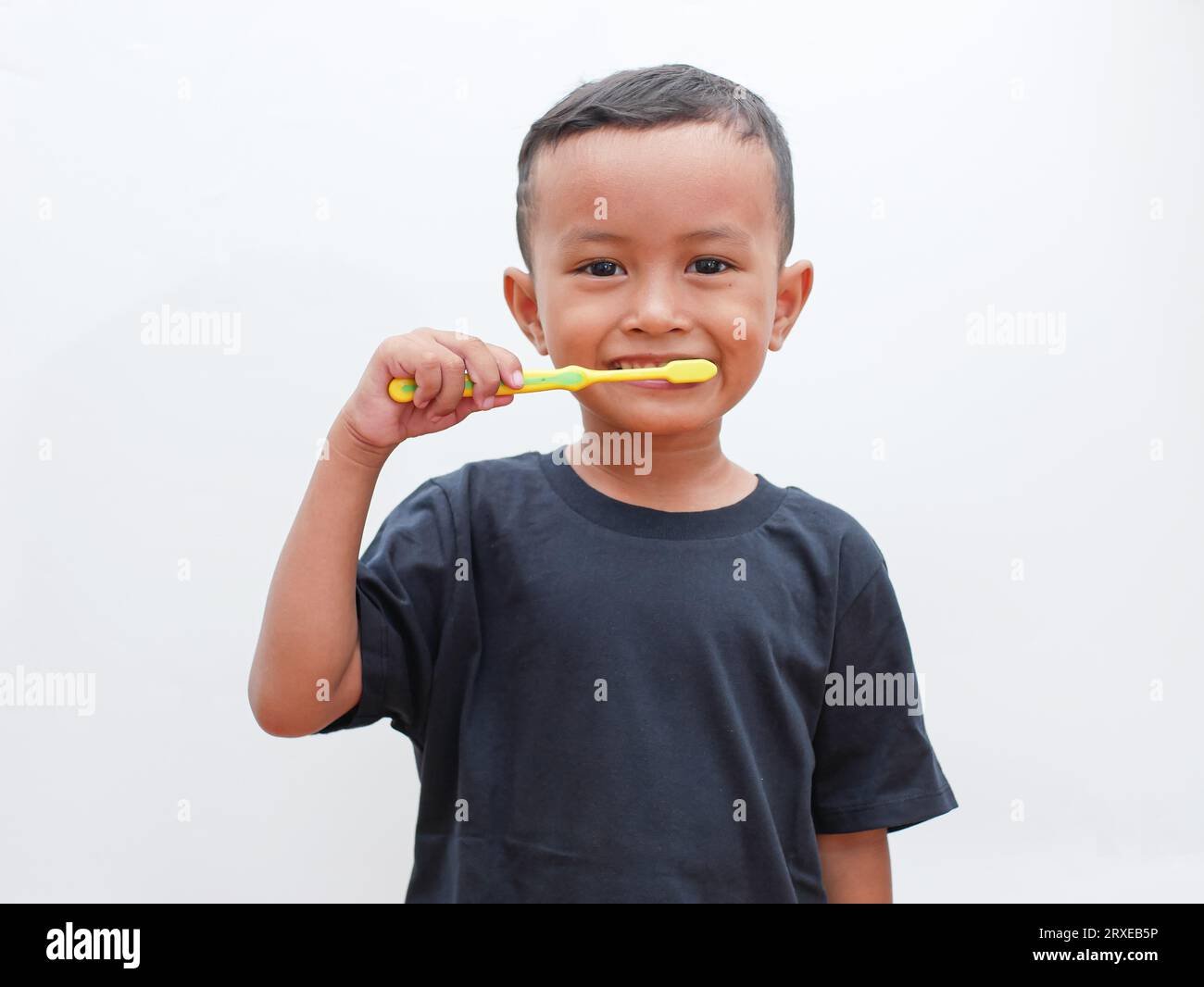 piccolo ragazzo asiatico che si pulisce i denti sorridendo su sfondo bianco con spazio per la copia. concetto di salute dentale per bambini Foto Stock