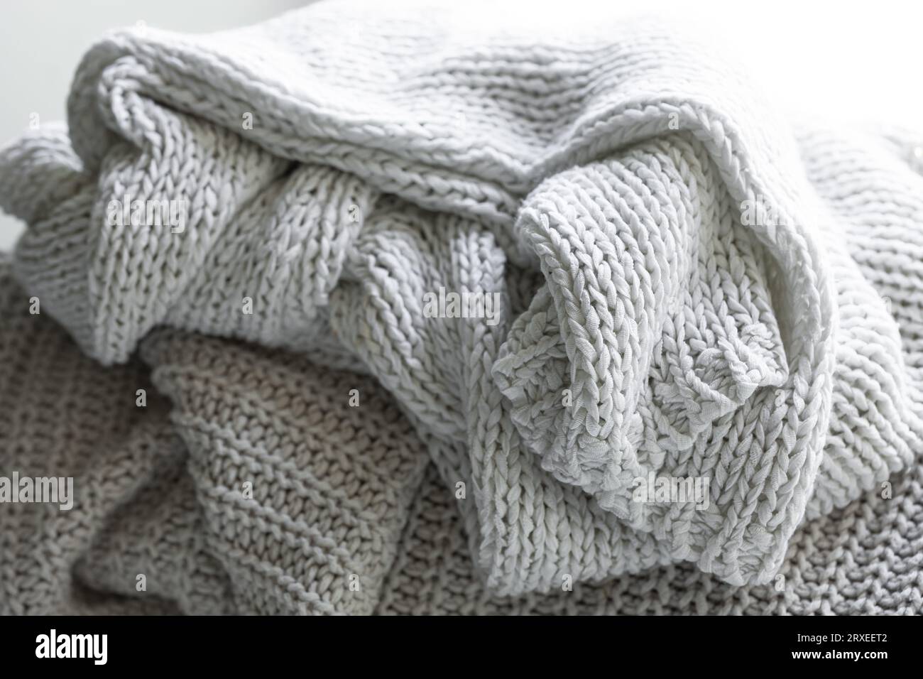 Maglione o sciarpa grigio caldo lavorati a maglia, composizione accogliente nell'atmosfera casalinga. Foto Stock
