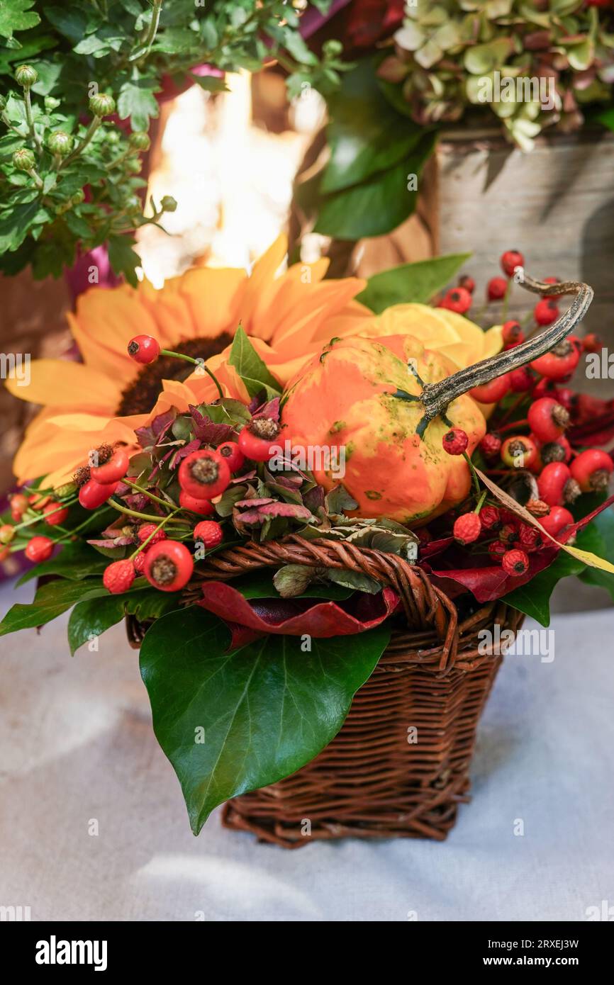 Bouquet autunnale di splendidi fiori, frutti di bosco e zucca nel cestino presso il fioraio all'aperto. Concetto di decorazione autunnale per il Ringraziamento Foto Stock