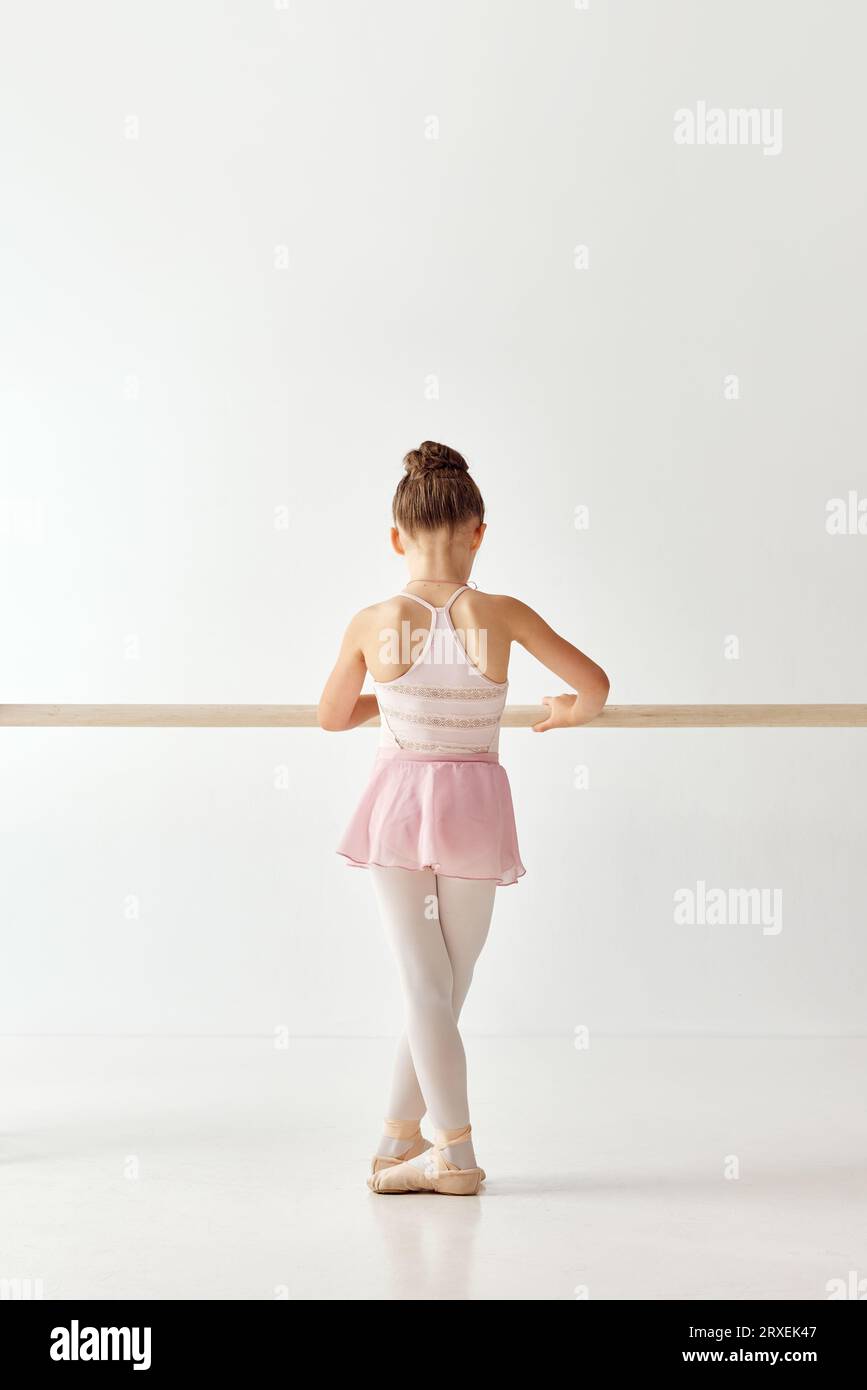 Ritratto posteriore di una piccola adorabile ballerina in tutu rosa con abito da ballo pointe, variante classica delle scarpe pointe. Lezioni di educazione nella danza Foto Stock