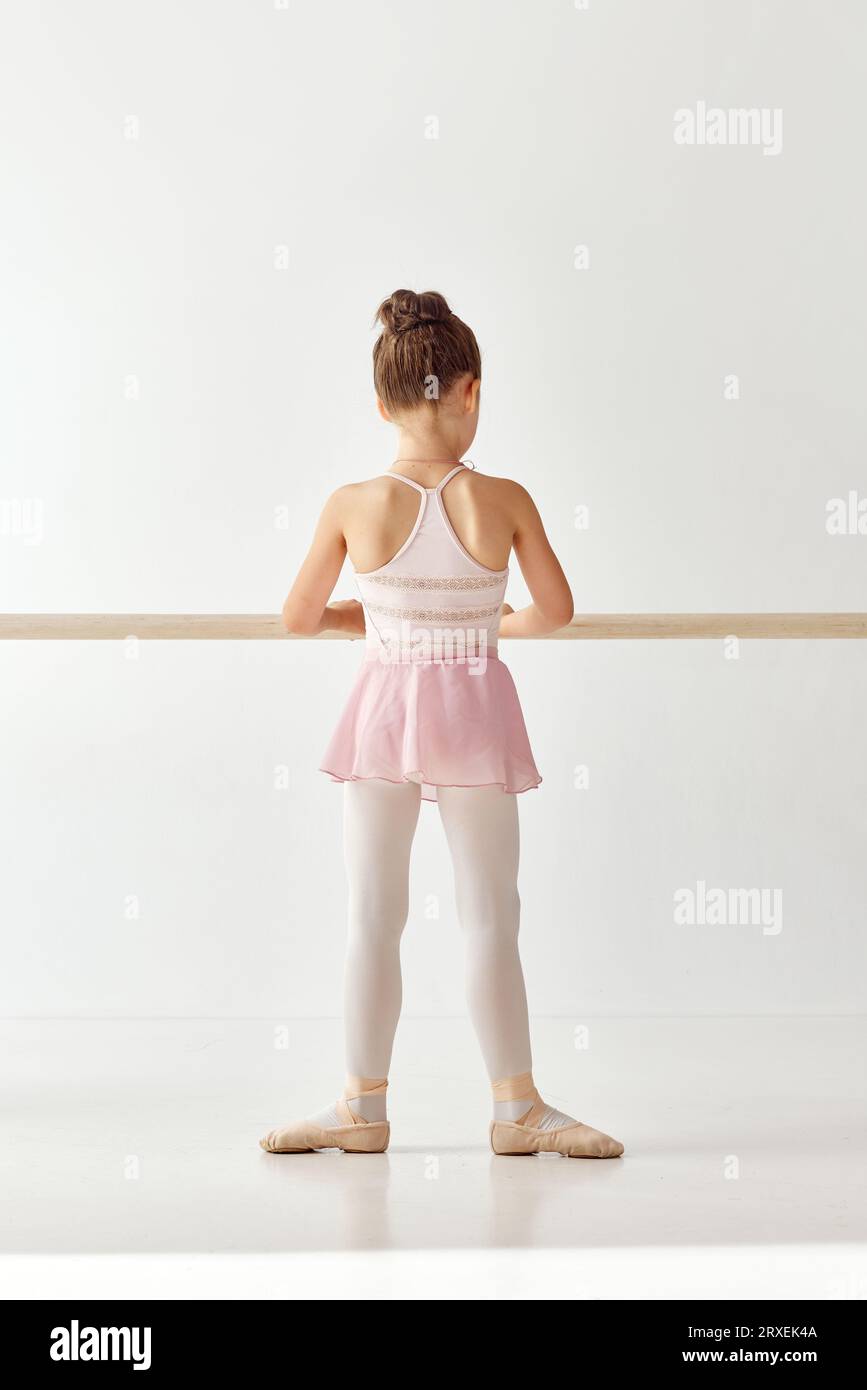 Ritratto retrovisivo di una piccola adorabile ballerina con abito da ballo tutu rosa, zampe bianche che si esercitano per l'esibizione. Lezioni di istruzione in Foto Stock