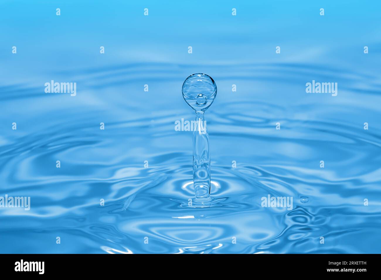 Gocce d'acqua limpida che spruzzano in cerchi concentrici, catturando una purezza rinfrescante. Foto Stock