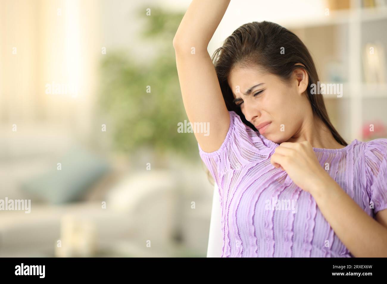 Donna con abiti puzzolenti che puzza sotto le braccia a casa Foto Stock
