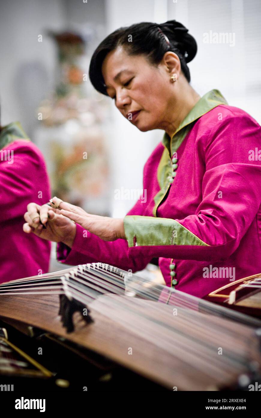 Una donna cinese in indumenti tradizionali suona GU-Zheng, uno strumento a corda pizzicato con le dita. Foto Stock