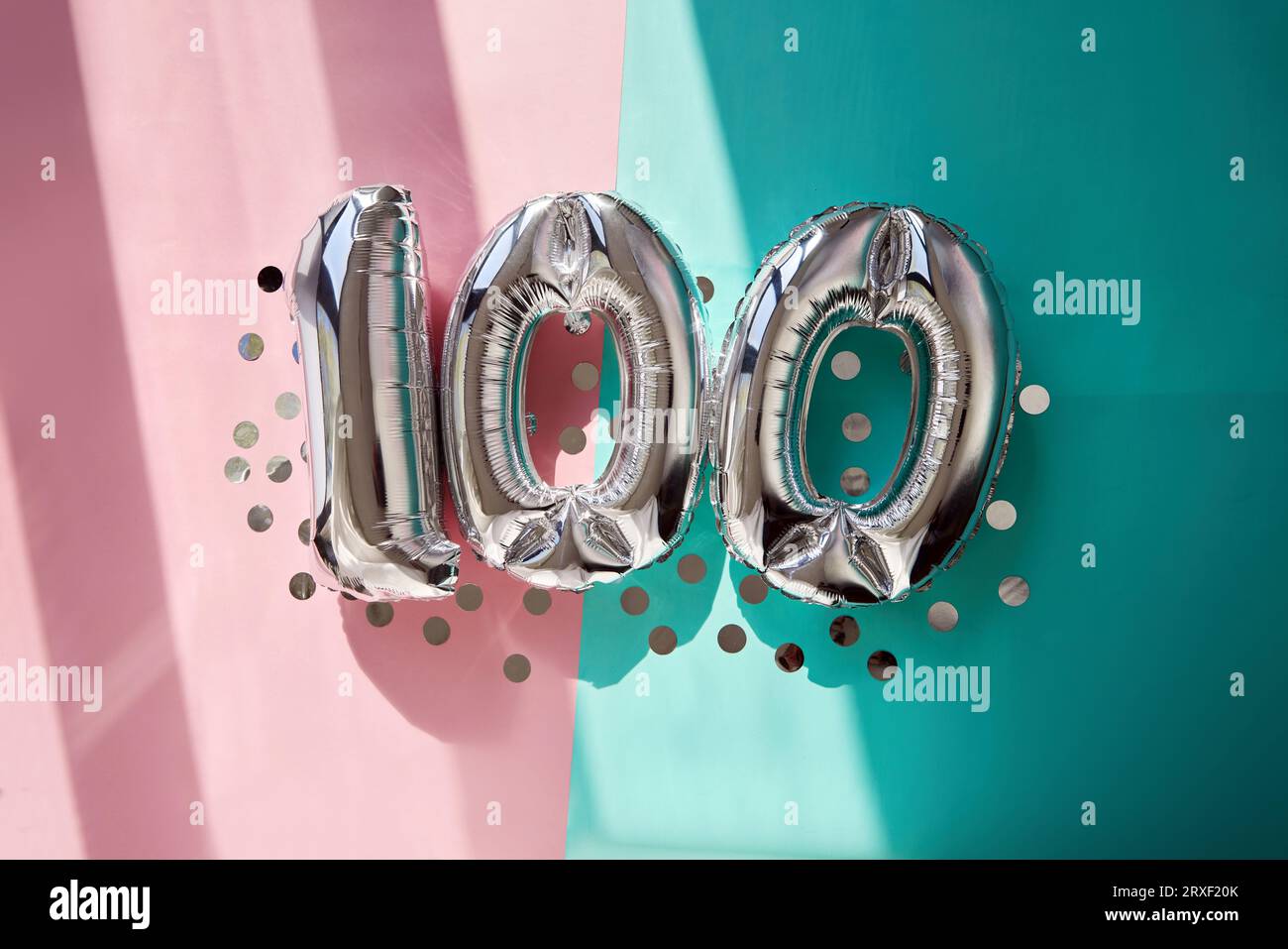 Silver Numbers 100 palloncini da cento anni sfondo turchese rosa luce solare Foto Stock