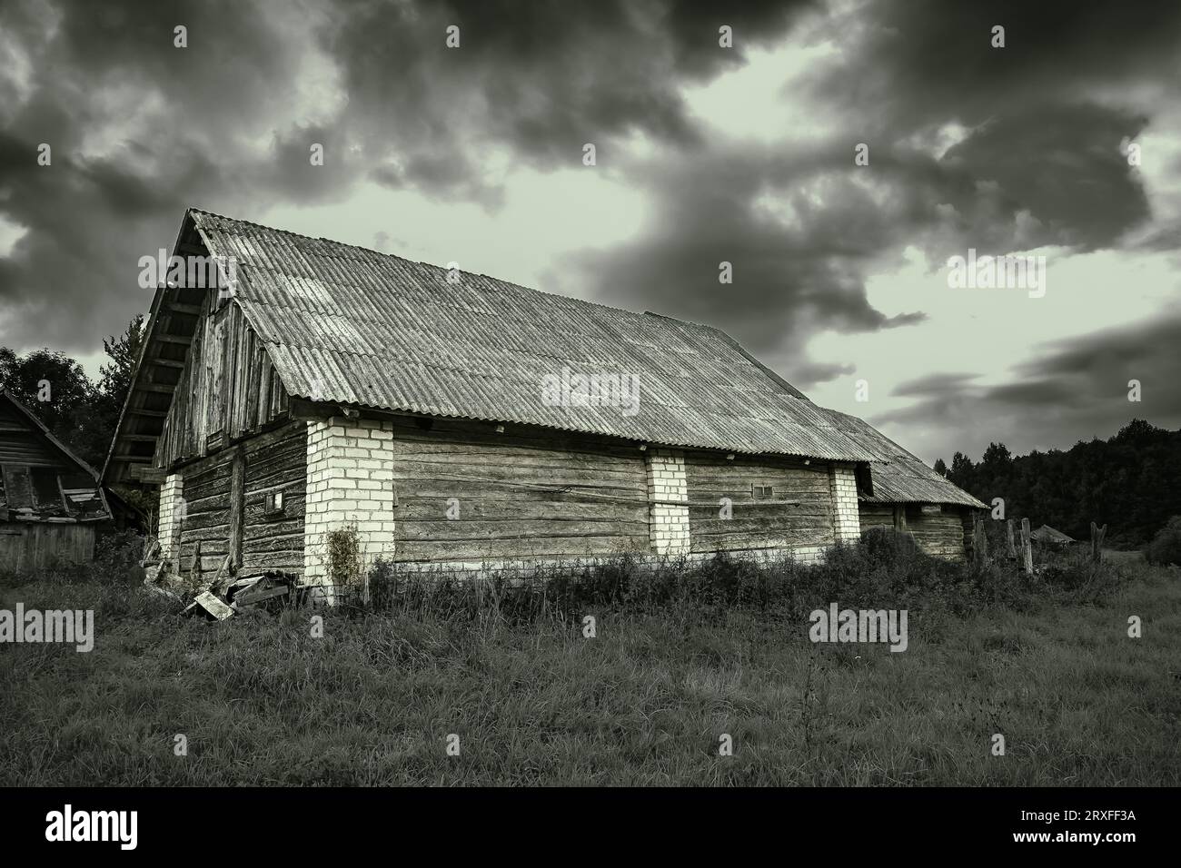 Vecchio edificio in disuso in un campo erboso e cielo nuvoloso. Infestato. Spaventoso. Foto Stock