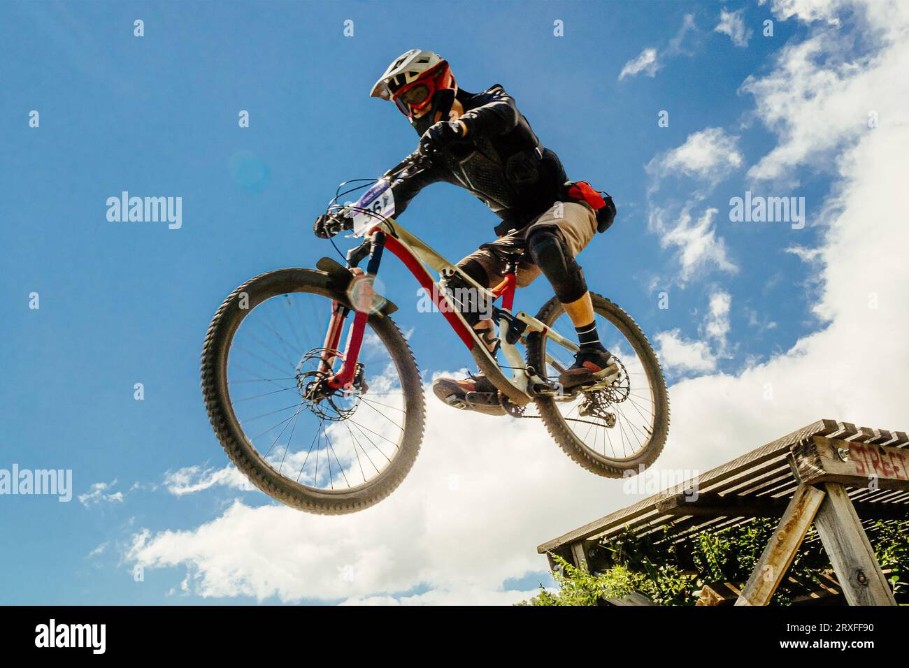 l'atleta di mountainbiker salta giù in volo. sullo sfondo del cielo blu Foto Stock