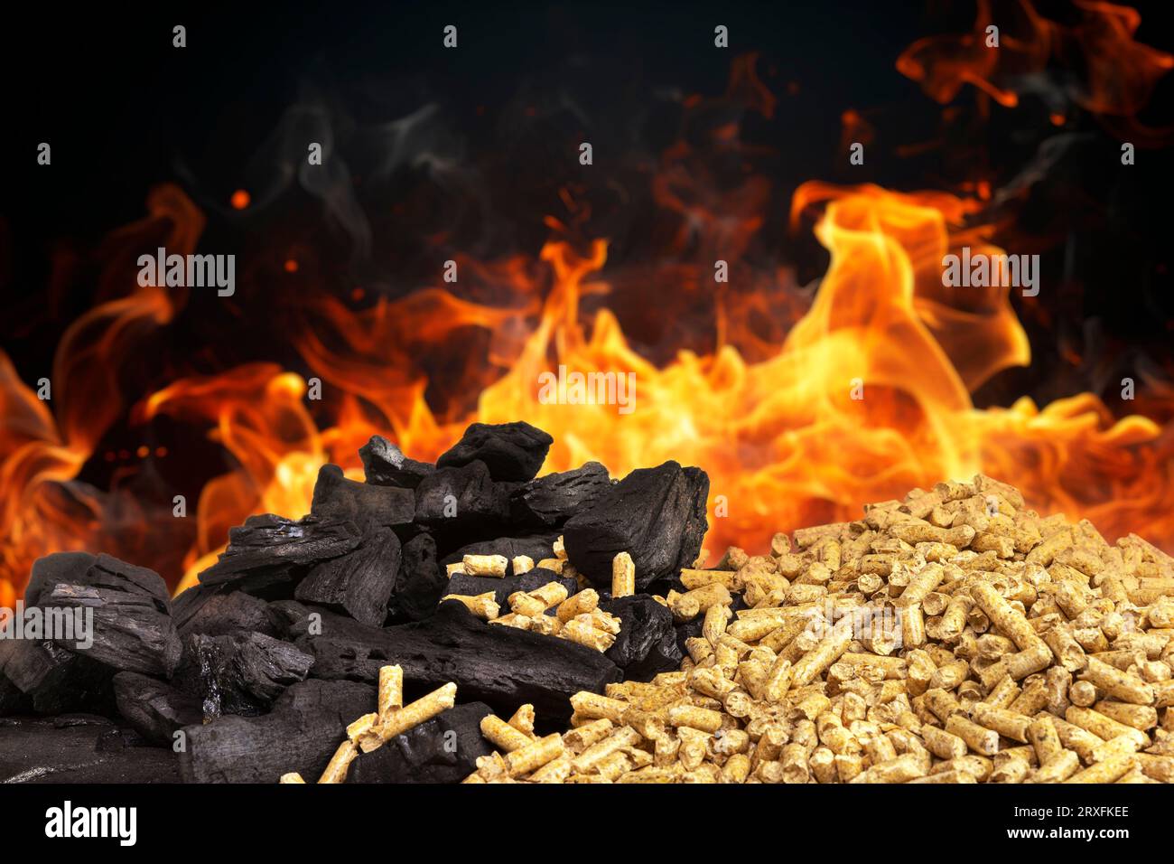 pellet di legno e pezzi di carbone con fiamme sullo sfondo Foto Stock