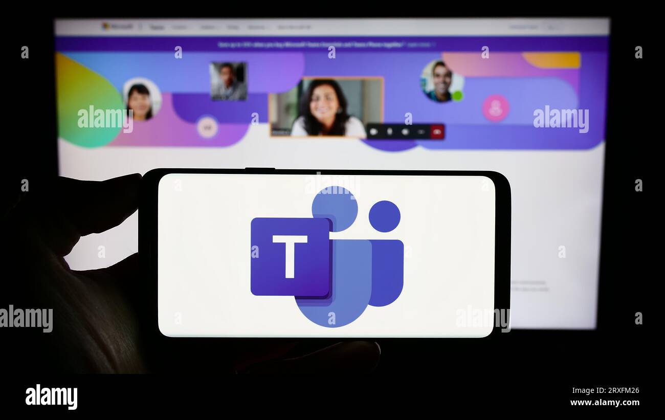 Persona che possiede il cellulare con il logo della piattaforma di comunicazione aziendale Microsoft Teams sullo schermo davanti alla pagina Web. Concentrarsi sul display del telefono. Foto Stock