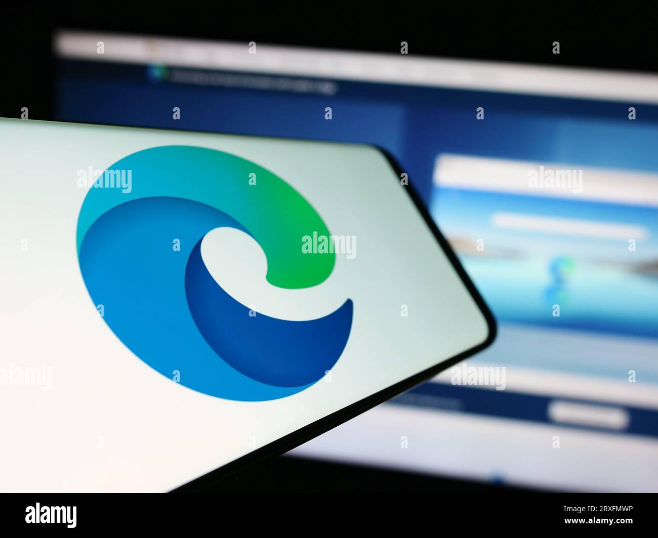 Telefono cellulare con logo del browser Web Microsoft Edge sullo schermo davanti al sito Web aziendale. Concentrarsi sul centro del display del telefono. Foto Stock