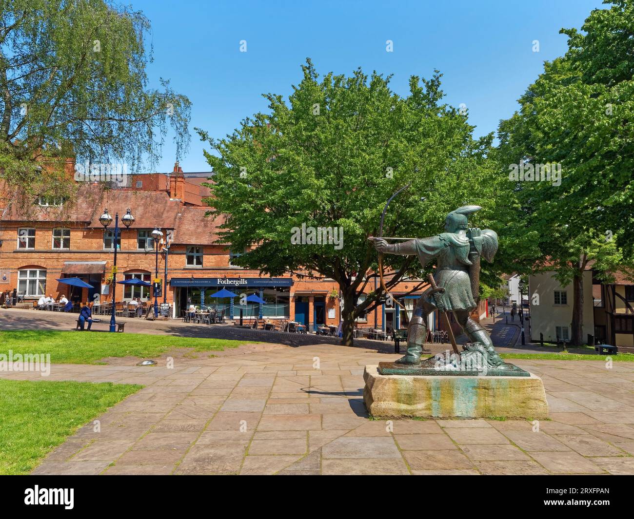 Regno Unito, Nottingham, Nottingham Castle, Statua di Robin Hood guardando verso Mortimer House e Fothergills Pub. Foto Stock