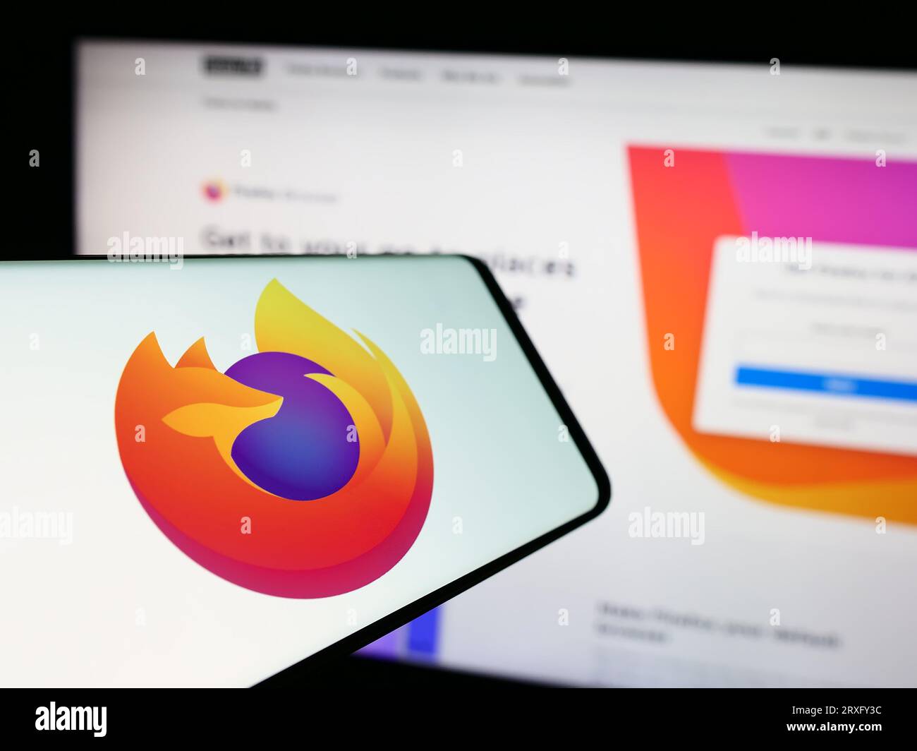 Telefono cellulare con logo del browser Web open source Mozilla Firefox sullo schermo davanti al sito Web. Concentrarsi sul centro del display del telefono. Foto Stock