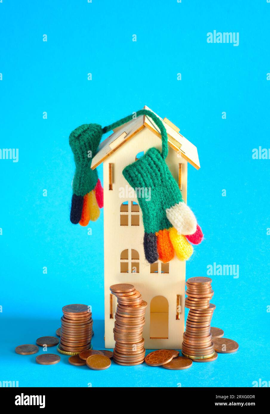 Casa modello con guanti invernali e pile di soldi.aumento dei costi di riscaldamento, isolamento termico e prezzi dell'energia a causa della carenza di gas di riscaldamento, petrolio e. Foto Stock