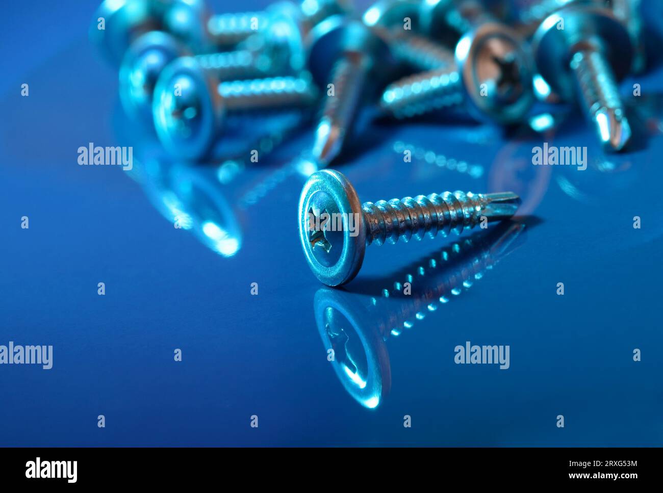 Viti di fissaggio in luce blu e su una superficie riflettente Foto Stock