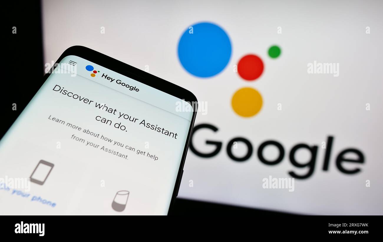 Smartphone con sito Web del software di assistenza virtuale Google Assistant sullo schermo davanti al logo aziendale. Mettere a fuoco in alto a sinistra sul display del telefono. Foto Stock