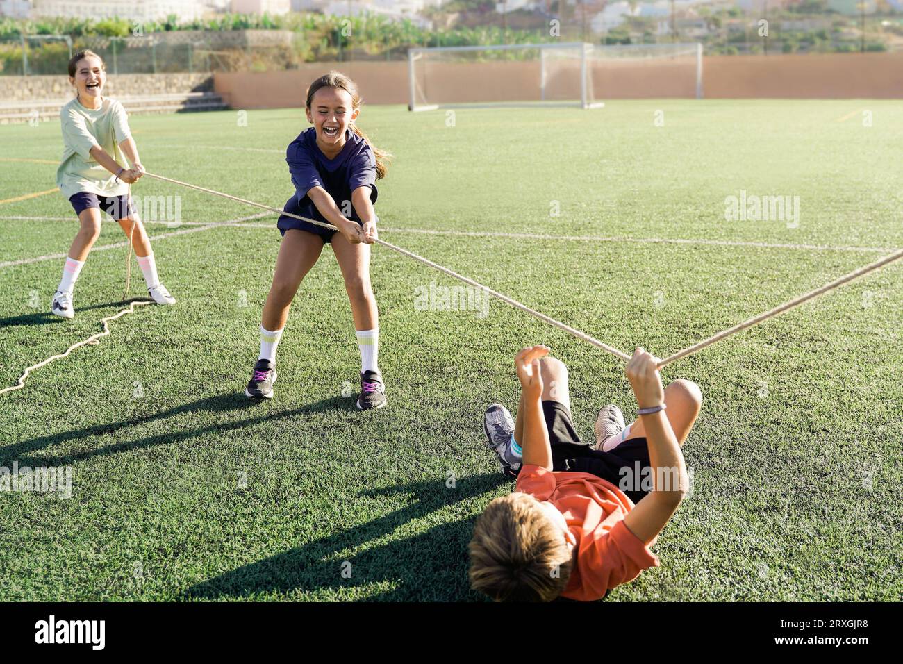 Gruppo di bambini che giocano all'aria aperta con il "rimorchiatore della guerra" - i bambini delle squadre sportive si divertono a giocare insieme Foto Stock