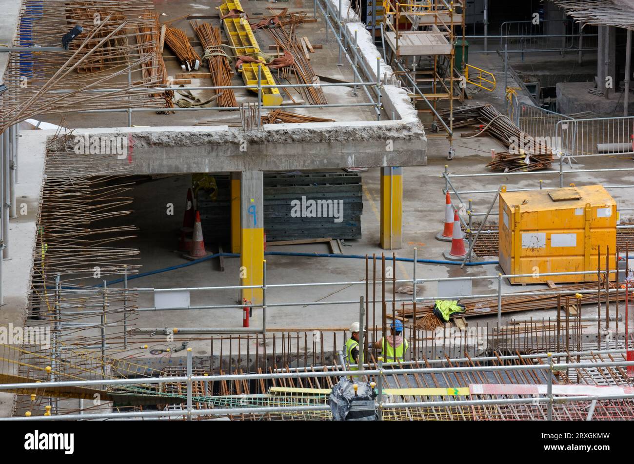 Lavori in corso in un cantiere, con due operai in primo piano Foto Stock