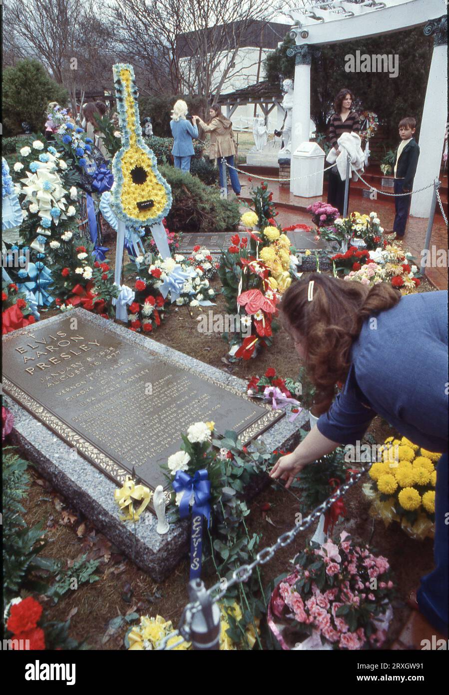 Al primo compleanno di Elvis dopo la sua morte, una donna mette un fiore sulla sua lapide. A Graceland, residenza di Elvis a Memphis, l'8 gennaio 1978 in un giorno di drizzly. Foto Stock