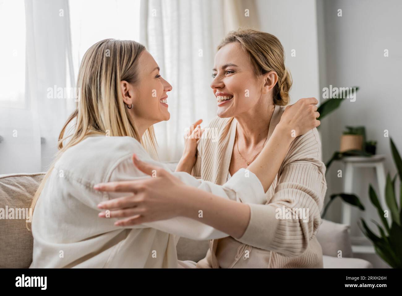 bellissime sorelle in un abbigliamento alla moda sorridenti che si guardano e si abbracciano, legano con la famiglia Foto Stock
