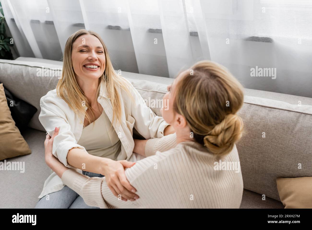 adorabili sorelle in abiti alla moda che ridono e si guardano l'un l'altra, mano su spalla, incollaggio Foto Stock