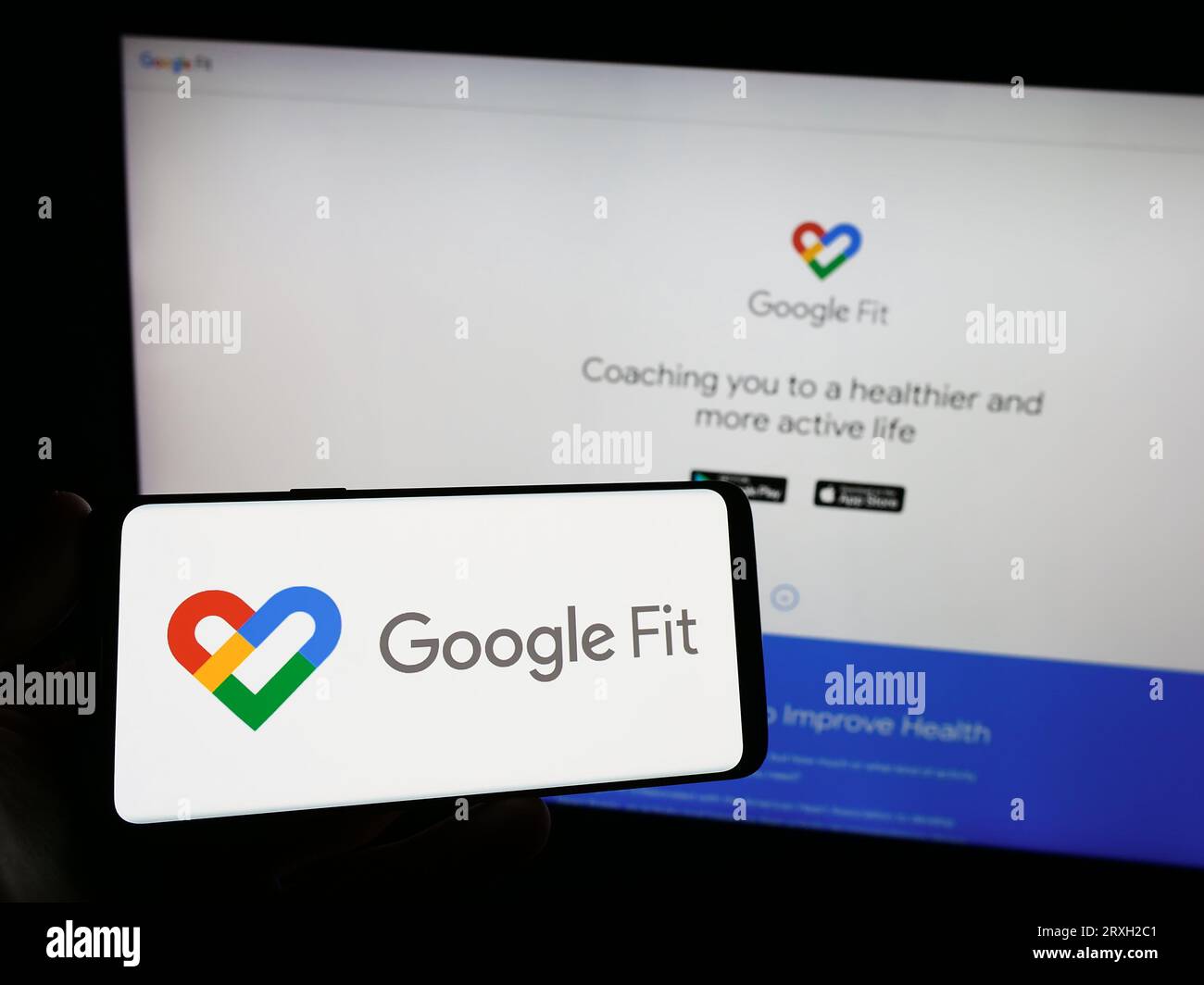 Persona che detiene lo smartphone con il logo del software di monitoraggio della salute Google Fit sullo schermo di fronte al sito web. Concentrarsi sul display del telefono. Foto Stock