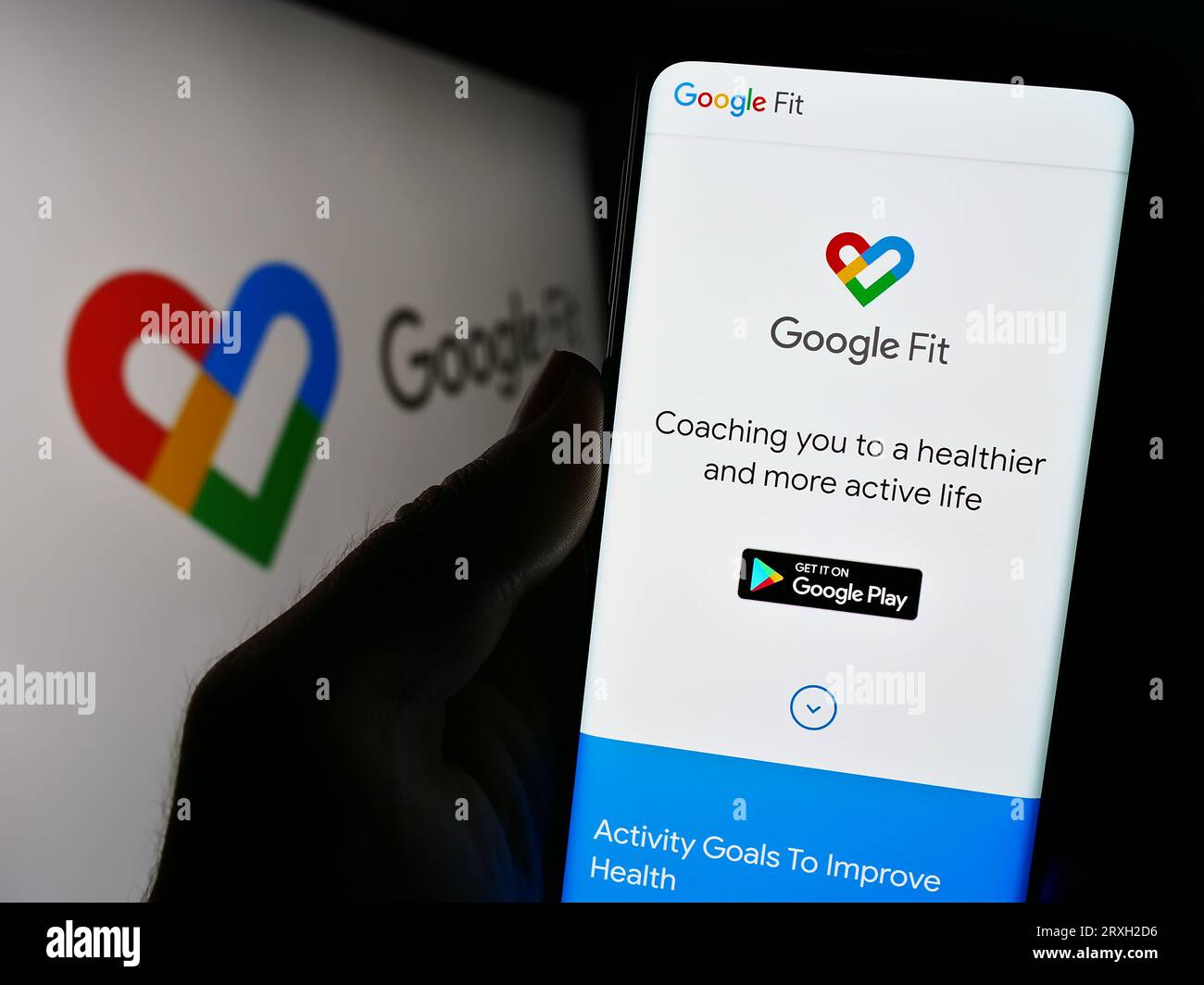 Persona in possesso di cellulare con pagina Web del software di monitoraggio della salute Google Fit sullo schermo davanti al logo. Concentrarsi sul centro del display del telefono. Foto Stock