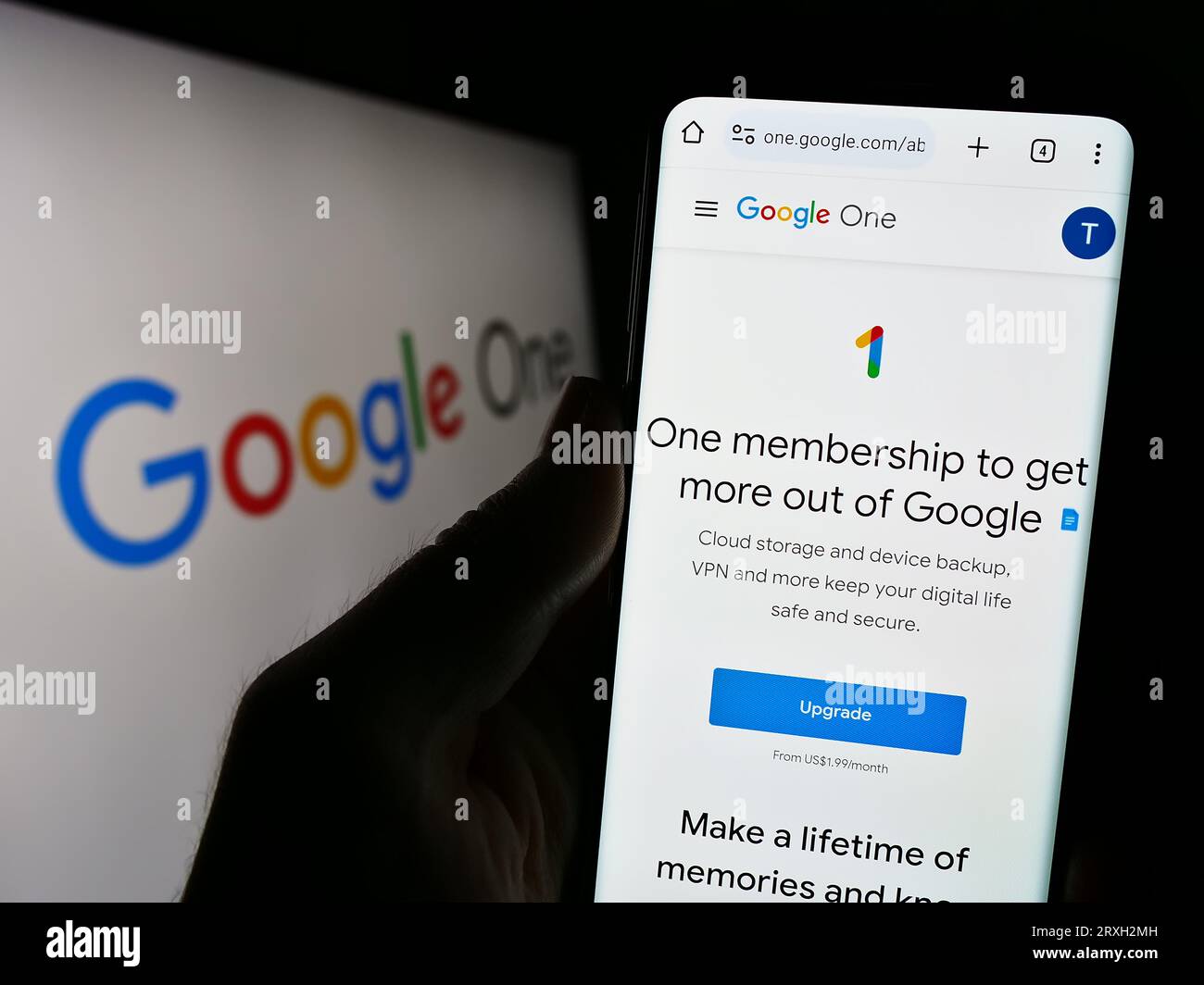 Persona che possiede uno smartphone con pagina Web del servizio di abbonamento software Google One sullo schermo davanti al logo. Concentrarsi sul centro del display del telefono. Foto Stock