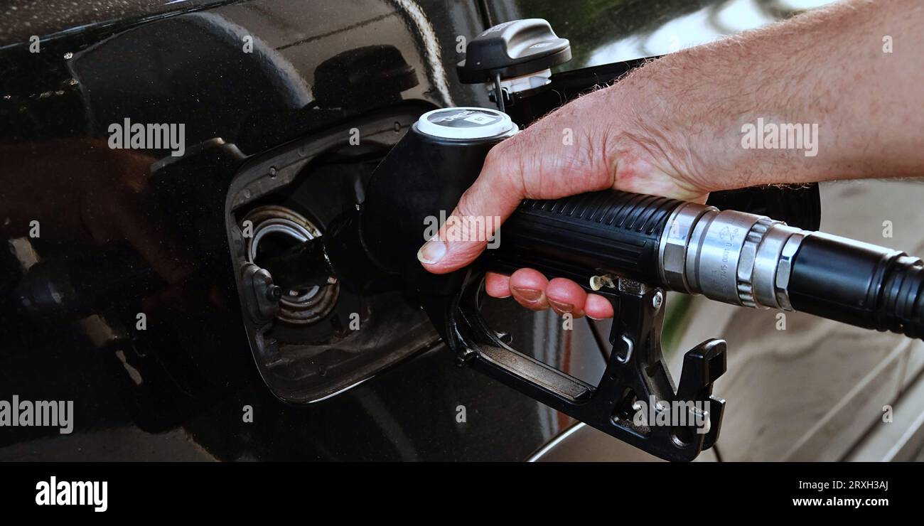 Rifornire l'auto, la mano di un uomo riempie il gasolio presso la stazione di servizio e la pompa di benzina riempie la pistola del carburante nel serbatoio dell'auto. Foto Stock