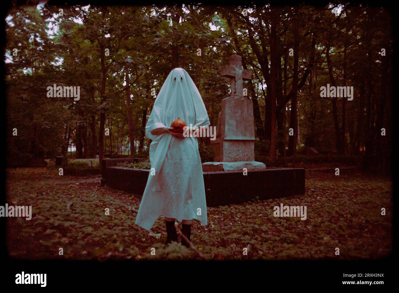 L'inquietante fotografia cattura una figura fantasma che tiene in mano la zucca di un martinetto mentre si trova in un cimitero al crepuscolo. Halloween, misticismo e orrore. La d Foto Stock