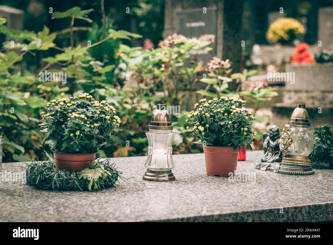 fiori decorativi, candele, corona sulla tomba del cimitero Foto Stock