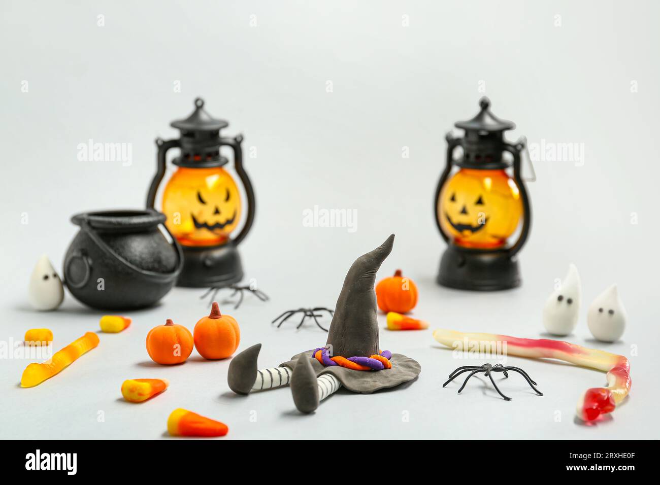 Composizione di Halloween con bambola strega, lanterne e caramelle dolci su sfondo grigio Foto Stock